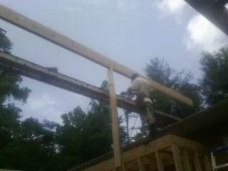 Carpenter setting a ridge beam over a new addition frame — Ice Dam Removal by Roofing Brothers in Ansonville