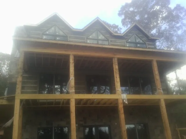 Dormers and porch framing on a large log home under construction — Roof Coating work by our crew in Ansonville