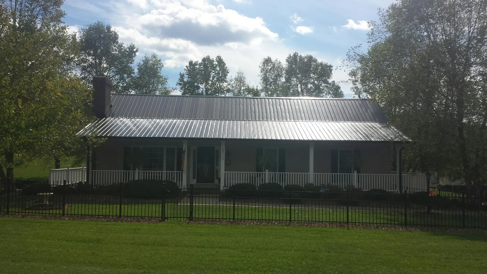 Gray metal roof on a brick ranch with a full width front porch — Gutter Guard Installation work by our crew in Ansonville