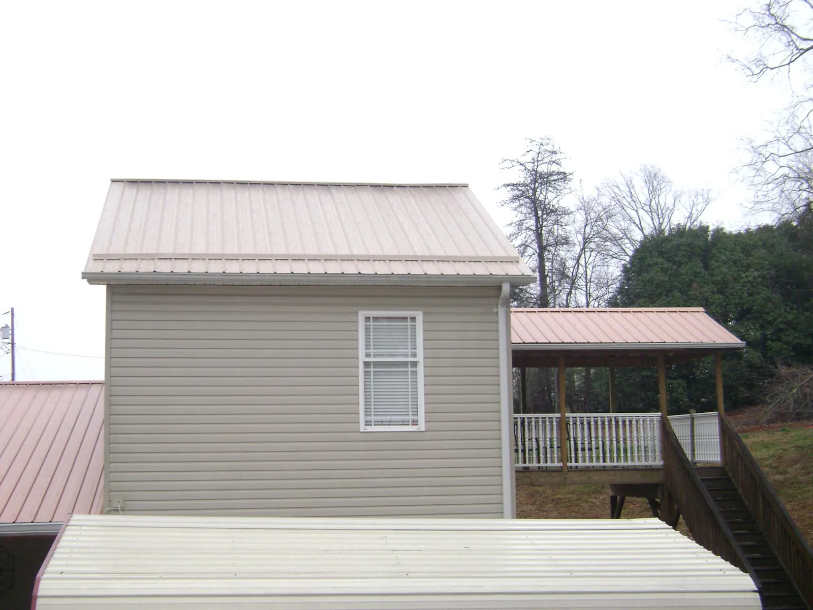 Tan metal roofs on a two story addition and attached porch, from a Roof Replacement job in Ansonville